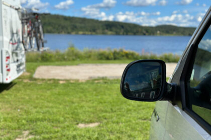 Van auf einem Stellplatz mit Blick auf einen See, daneben ein Wohnmobil.