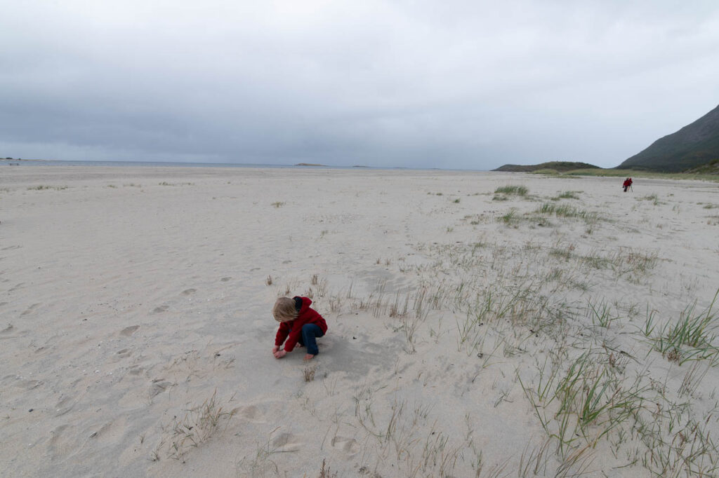 Ein kleines Kind spielt an einem großen, leeren Strand.