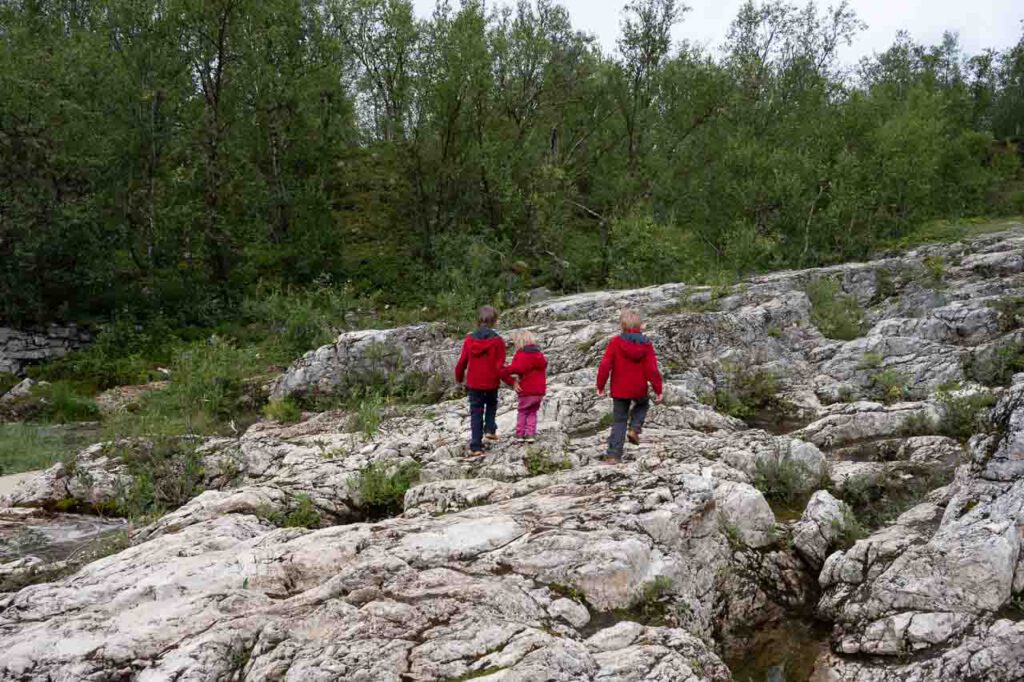 Drei Kinder laufen auf Felsen.