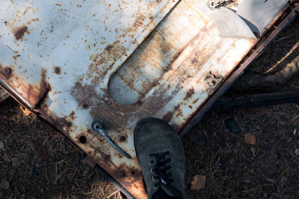Ein Fuß steht auf einem Stück alter Autokarosse