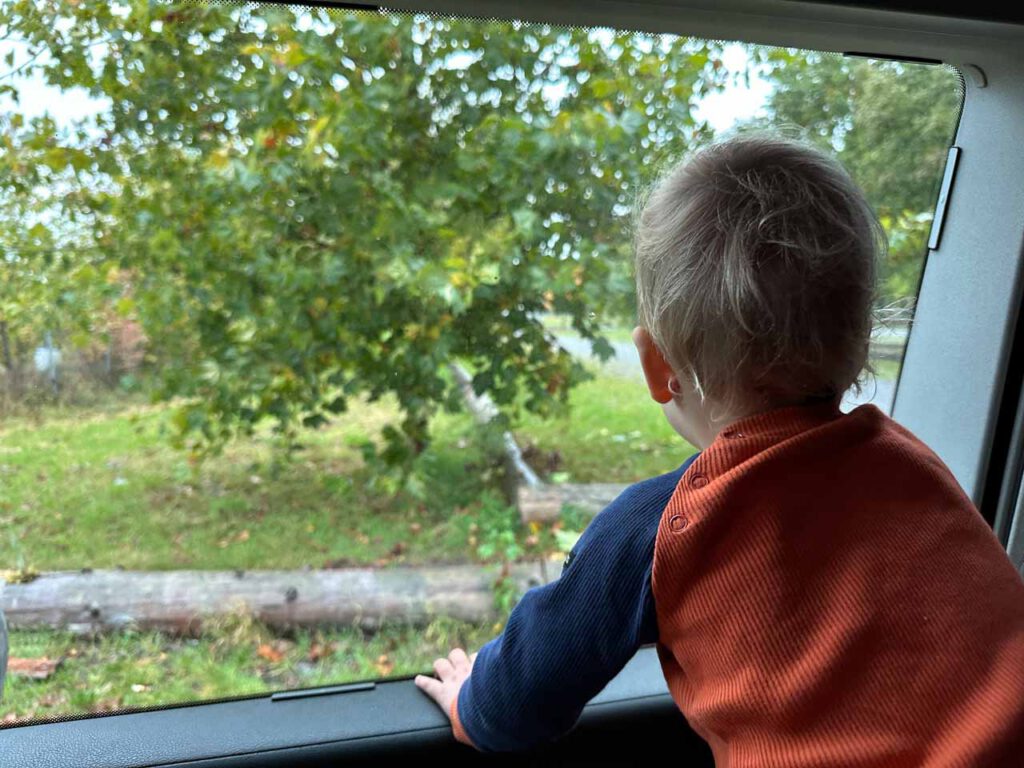 Ein Kleinkind schaut aus dem Fenster eines Campingbusses.
