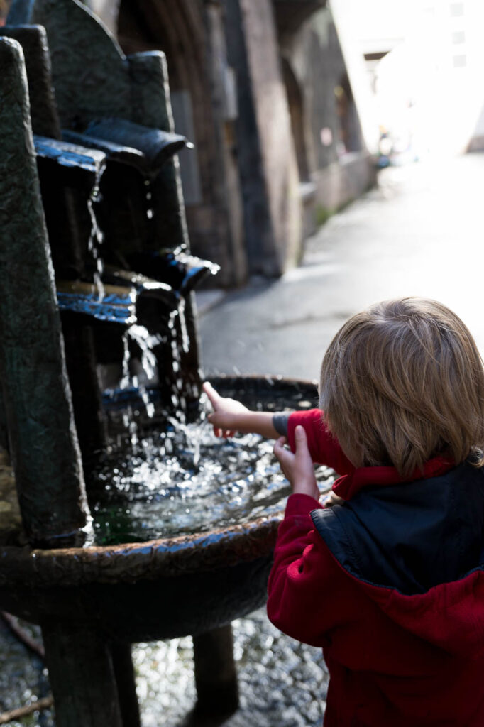Kinder spielen an einem Stadtbrunnen.