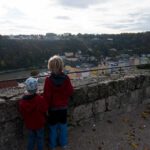 Zwei Kinder schauen über die Mauer einer Burg ins Tal.
