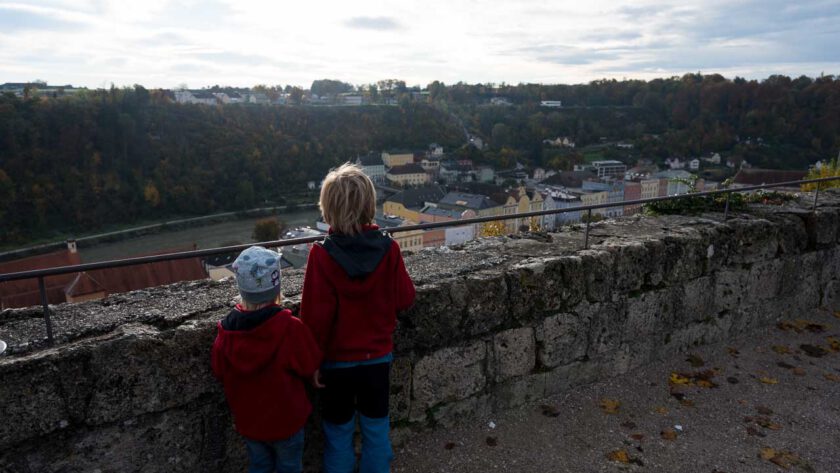 Zwei Kinder schauen über die Mauer einer Burg ins Tal.
