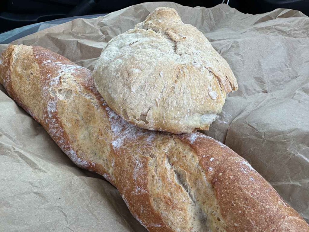 Ein Baguette und ein rundes Brot auf einem braunen Papier